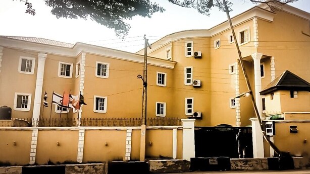 A multi-story building with a yellow facade, multiple windows, and a gated entrance. - Cameo's Suites (Lagos)