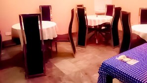 A hotel room with a round dining table, a smaller round table, and a bed with a blue checkered bedspread. - Cameo's Suites (Lagos)