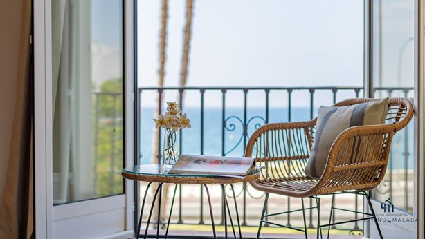 A balcony with wicker chairs, a glass table, and a vase with flowers. - Seafront Duplex Living4malaga (Málaga)