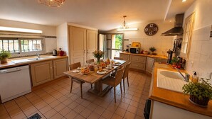 A modern kitchen with a dining area, featuring a large clock, a coffee maker, and a sink.
