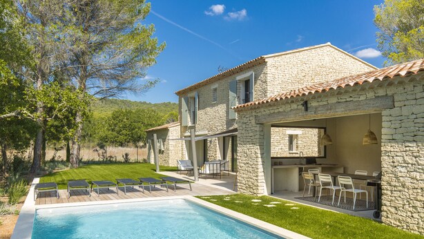 Une villa en pierre dotée d’une piscine, d’un espace extérieur aménagé et offrant une vue sur le paysage environnant.
