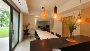 Une cuisine moderne dotée d’un grand îlot central, de luminaires suspendus et offrant une vue sur l’extérieur.