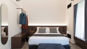 Quarto de hotel moderno com uma cama grande, mesas de cabeceira, um espelho e um guarda-roupa.