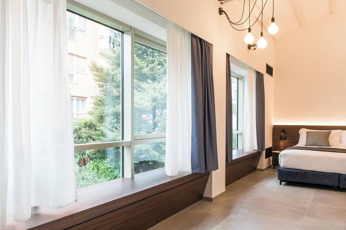 Un dormitorio moderno con un ventanal grande, una cama y una mesita de noche.