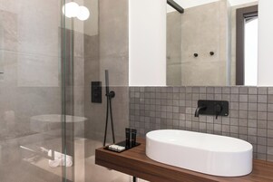 Un baño moderno con un lavabo blanco, una mampara de ducha de vidrio y un espejo sobre el lavabo.