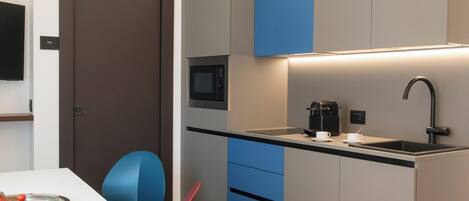 A modern kitchen with a microwave, coffee maker, and sink.