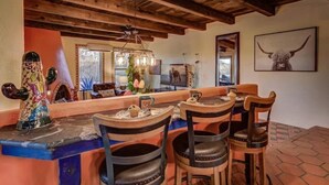 A rustic dining area with wooden chairs and a bar counter, featuring a chandelier and a bull's head artwork on the wall. - Year Around Heated Pool, Mountain Views, Pets Ok (Las Cruces)