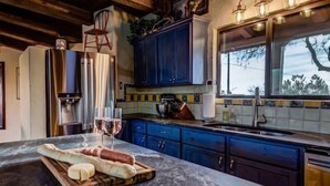 A kitchen with marble countertops, a wooden cutting board with bread and cheese, and a wine glass. - Year Around Heated Pool, Mountain Views, Pets Ok (Las Cruces)