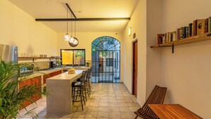 Une cuisine moderne dotée d’un îlot central, de tabourets de bar, d’une table à manger en bois et d’une bibliothèque.