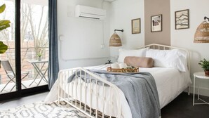 A bedroom with a bed, a bedside table, a window, and a balcony. - *NEW* The Jolene - Walkable | Ponce City (Atlanta)