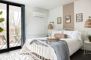 A bedroom with a bed, a bedside table, a window, and a balcony.