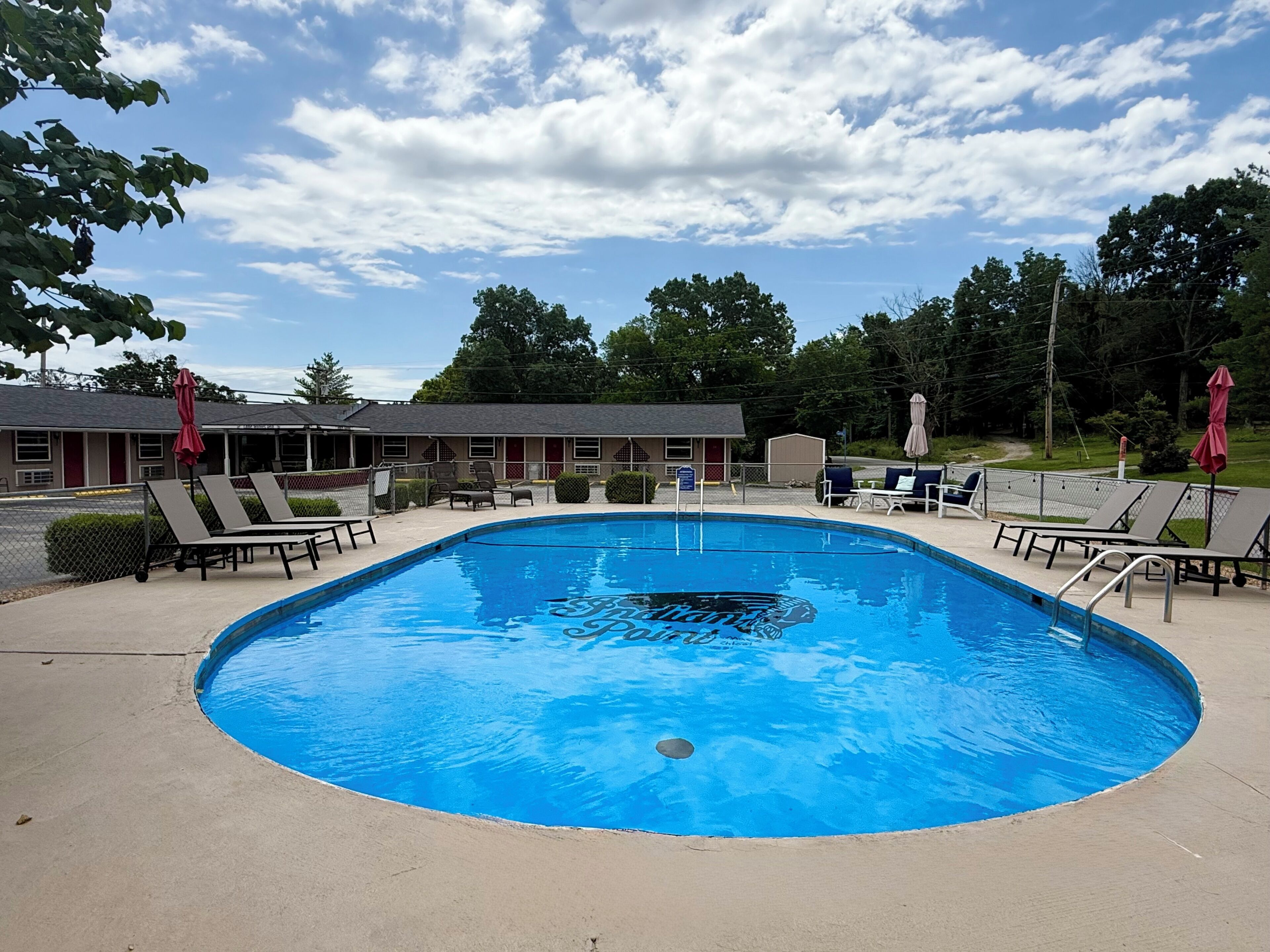 A swimming pool with lounge chairs and a motel in the background.