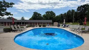 A swimming pool with lounge chairs and a motel in the background.