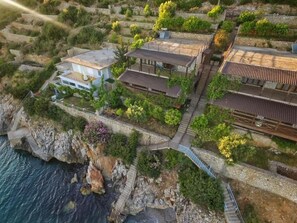 A coastal property with terraced gardens, a wooden deck, and a stone pathway leading to a building with a tiled roof. - Seaside Duplex Stone Villa (Lukovë)