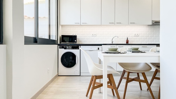 A modern kitchen with a washing machine, dishwasher, and microwave.