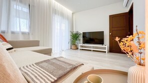 A modern living room with a sofa, TV, and a potted plant.