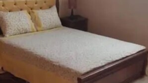A bed with a wooden frame and a white bedspread.