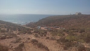 A coastal landscape with a parking area and a building on a hill.