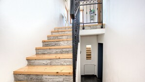 A staircase with wooden steps and stone walls, leading to a room with a radiator and a door.