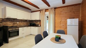 A modern kitchen with white cabinets, a microwave, and a stove. There is a dining area with a table and chairs, and a refrigerator. - House 2233/68573 (Istria - Vodnjan), 10000m from the beach (Vodnjan)