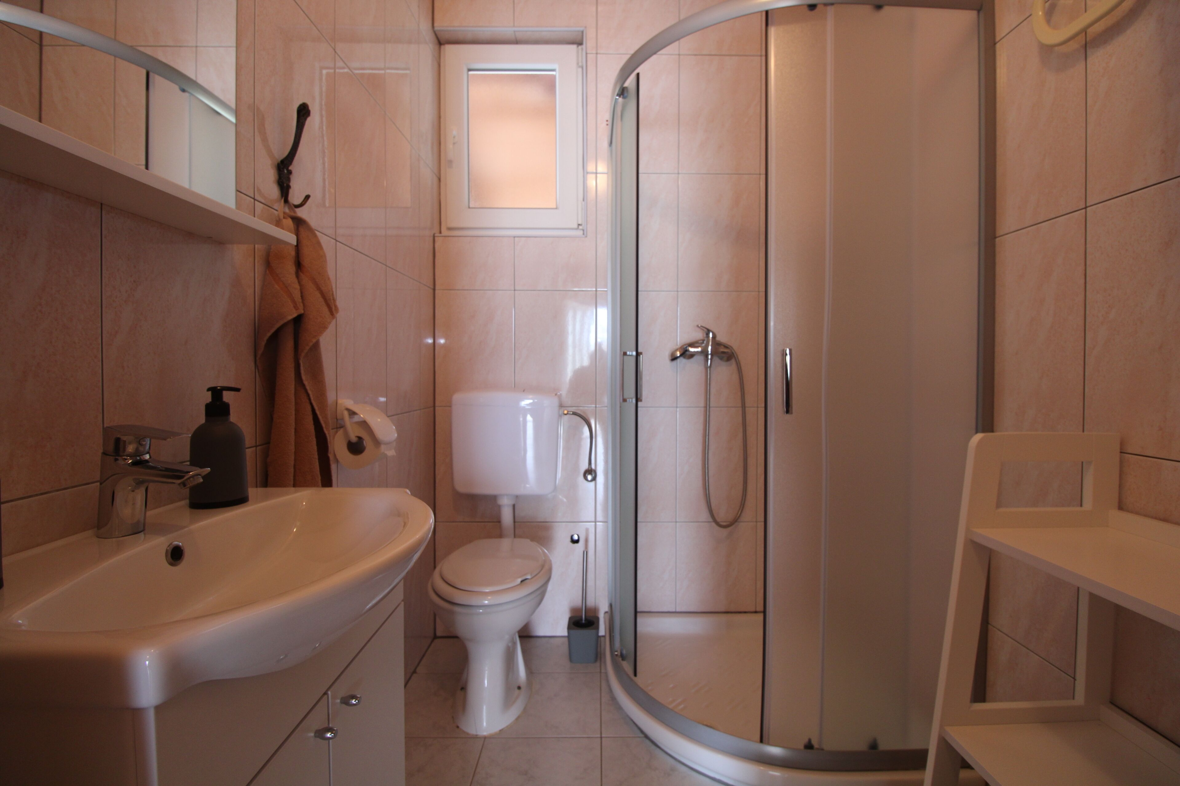 Un bany modern amb una dutxa de forma corba, un lavabo blanc i un vàter.