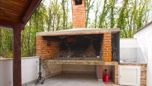 An outdoor brick oven with a stone countertop, a sink, and a red bucket. - House 2233/68573 (Istria - Vodnjan), 10000m from the beach (Vodnjan)