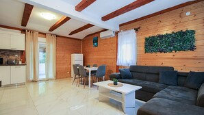 A modern living room with a sofa, a dining table with chairs, a kitchen area, and a decorative wall. - House 2233/68573 (Istria - Vodnjan), 10000m from the beach (Vodnjan)