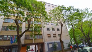 Un immeuble à plusieurs étages doté de balcons, d’un espace de stationnement et d’arbres à l’avant.