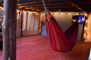 A hammock in a wooden room with a red floor, exposed beams, and string lights. - Chillhouse pisac (Pisac)