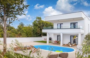 Ein modernes, zweistöckiges Haus mit Swimmingpool, Außenbereich und Balkon.