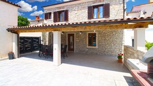 A stone house with a covered patio, a black gate, and outdoor seating. - House 2249/69836 (Istria - Liznjan), 1500m from the beach (Liznjan)