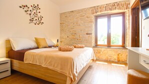 A bedroom with a stone wall, wooden bed, and a window with a view. - House 2249/69836 (Istria - Liznjan), 1500m from the beach (Liznjan)