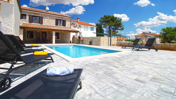 A poolside area with lounge chairs, a stone building, and a clear blue sky. - House 2249/69836 (Istria - Liznjan), 1500m from the beach (Liznjan)