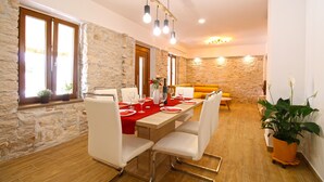 A dining area with a stone wall, wooden flooring, and a table set for four with white chairs. - House 2249/69836 (Istria - Liznjan), 1500m from the beach (Liznjan)