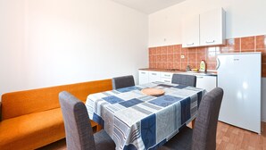 Cocina compacta con armarios blancos, un refrigerador blanco y un salpicadero de azulejos.