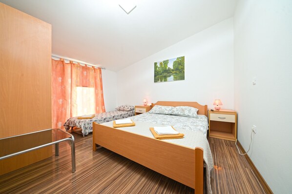 Un dormitorio con una cama grande, dos mesitas de noche con lámparas, un armario de madera, una silla y una ventana con cortinas.