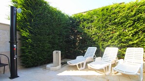 Un pati amb tres seients blanqus, un pal negre i una petita jardinera blanca.