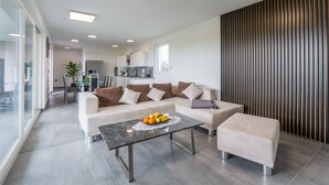 A modern living room with a sofa, ottoman, and coffee table. There is a fruit bowl on the table. - House 2258/73634 (Istria - Valbandon), 1500m from the beach (Valbandon)