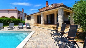 A poolside area with lounge chairs, a swimming pool, and a building with stone pillars and a tiled roof. - Villa 2273/75669 (Istria - Liznjan), 800m from the beach (Liznjan)
