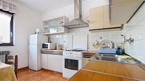 A compact kitchen with white cabinets, a stove, a microwave, and a sink. - Apartment 2276/75855 (Istria - Pula), 3500m from the beach (Pula)