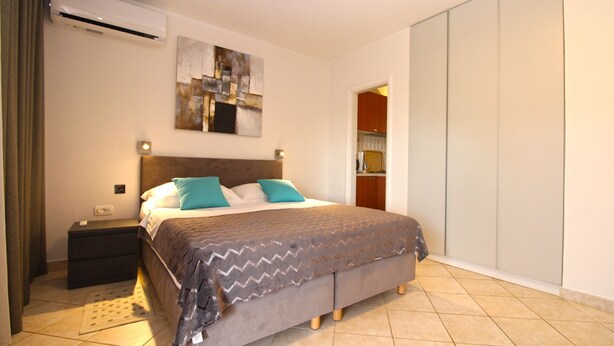 A bedroom with a bed, nightstand, and an air conditioning unit. - Apartment 2277/75908 (Istria - Premantura), 300m from the beach (Premantura)