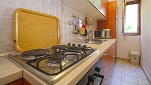 A kitchen with a gas stove, a microwave, and a sink. - Apartment 2277/75908 (Istria - Premantura), 300m from the beach (Premantura)