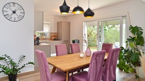A modern kitchen with a wooden table and purple chairs, a clock on the wall, and a balcony with plants. - House 2279/75934 (Istria - Medulin), 350m from the beach (Medulin)