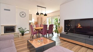 A modern living room with a fireplace, a dining area with chairs, a TV, and a clock on the wall. - House 2279/75934 (Istria - Medulin), 350m from the beach (Medulin)