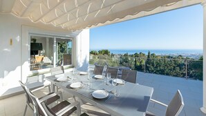A dining area with a table set for six, overlooking a scenic view of the sea and cityscape. - Stunning Villa with Panoramic Views of the Med (Mijas Pueblo)