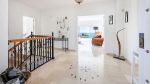 A spacious hallway with a wooden staircase, a decorative floor pattern, and a view to a balcony. - Stunning Villa with Panoramic Views of the Med (Mijas Pueblo)
