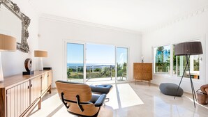 A spacious room with a large window, a wooden cabinet, a modern chair, and a floor lamp. - Stunning Villa with Panoramic Views of the Med (Mijas Pueblo)