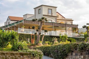 Enjoy a serene view from the spacious balcony overlooking lush greenery and a stone wall.