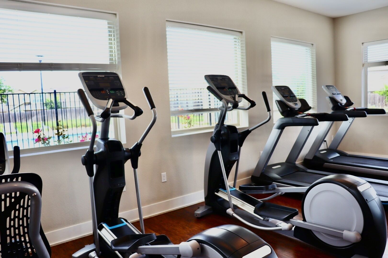Une salle de sport équipée de trois tapis de course, d’un vélo elliptique et d’un vélo d’appartement.