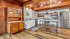 A kitchen with wooden cabinets, a stainless steel refrigerator, and a bar stool. - Book-Me-By-The-Lake (Morgantown)